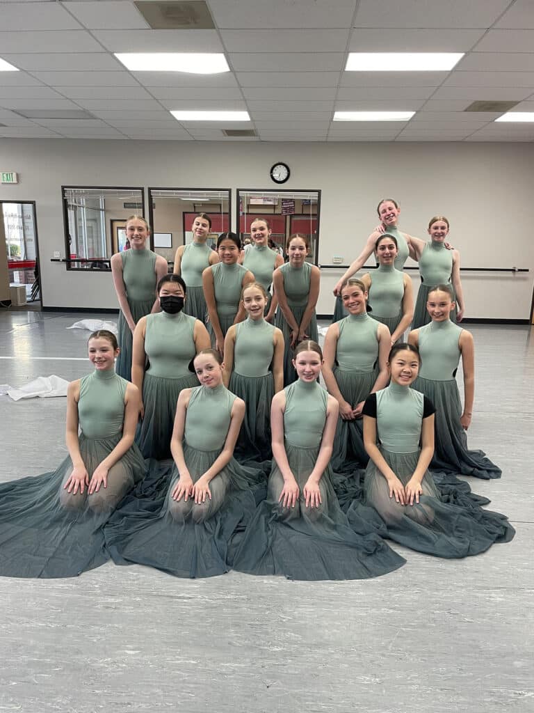Teen dance group posing in sage green costumes during costume week at the studio